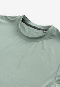 Camiseta de manga corta color verde menta hecha de una tela texturada, con un escote redondo y un cuello interior negro en contraste.