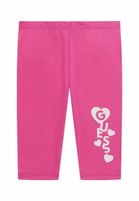 Roze leggings van zachte stof, met een witte grafische opdruk die "GUESS" spelt met harten, en een elastische tailleband voor comfort.
