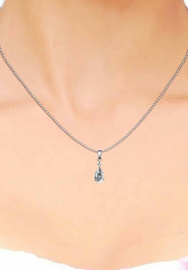 Collana in argento con pendente a forma di goccia contenente una pietra preziosa trasparente, evidenziando dettagli intricati e una finitura lucida.