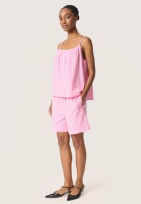 Top de rayas rosas y blancas con tirantes finos y pantalones cortos a juego. El material parece fresco, con un corte relajado y cintura con cordón.