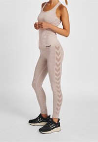 Vaaleanbeige urheilullinen tankkitoppi ja legginssit, joissa on tekstuurisia kuvioita. Legginseissä on kalanruotokuvio sivuilla. Mustat lenkkarit täydentävät asun.
