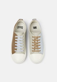 Two low-top casual sneakers with cream, brown, and light blue panels, contrasting laces, and branded insoles reading "CAMPER" and "TWINS."