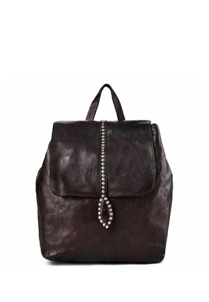 Sac à dos en cuir marron foncé avec une fermeture à rabat présentant une rangée verticale de clous métalliques et une languette en cuir bouclée.