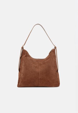 Sac à épaule en daim marron avec une bandoulière unique, un design simple et une fermeture éclair sur le dessus, sur un fond clair uni.