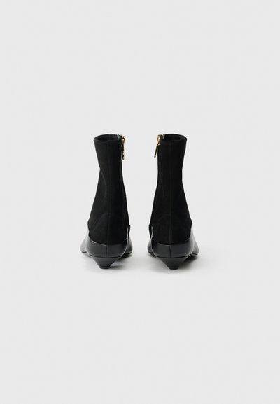 Czarne zamszowe botki za kostkę z gładką czarną gumową podeszwą, z zapięciem na zamek oraz zwężającym się obcasem.