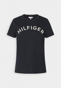 Černé bavlněné tričko s krátkým rukávem, na kterém je vyšívaný nápis "HILFIGER" bílou barvou přes prsa. Klasický kulatý výstřih, standardní střih.