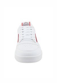 Baskets blanches avec accents rouges sur les côtés, laçage à l'avant, bout perforé pour la respirabilité, semelle plate et logo Kappa sur la languette.