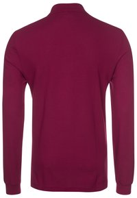 Camisa tipo polo de manga larga en burdeos con cuello, textura suave y color sólido. Presenta cuello y puños de canalé.