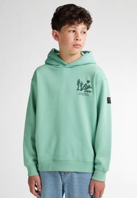 Felpa verde menta con tasca a marsupio, polsini e orlo a coste, caratterizzata da un design grafico nero sulla parte anteriore e un'etichetta con logo sulla manica.