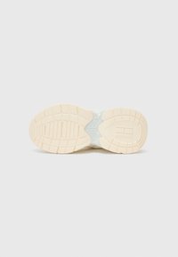 Semelle de chaussure en matériau en caoutchouc beige, avec un motif texturé, des accents courbes et des rainures pour une adhérence optimale. Section centrale lisse.
