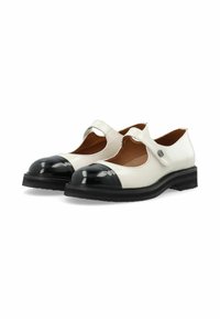 Zapatos de cuero blanco con una puntera redondeada de charol negro y una correa que cruza el empeine; parte superior texturizada con una suela plana de goma negra.