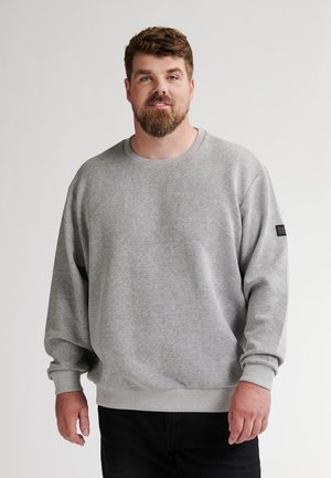 Grijze sweatshirt met een gestructureerd ruitpatroon, geribde manchetten en een ronde hals, gecombineerd met donkere jeans.