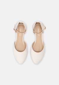 Zapatos planos blancos con punta afilada, correa al tobillo y hebilla dorada. Acabado de cuero suave con un forro interior beige claro.