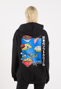 Black hoodie featuring a colorful graphic on the back, depicting various Japanese dishes against a blue background, including ramen and sushi.