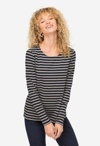 Chemise à manches longues rayée en bleu marine et gris clair, dotée d'un col rond et d'une texture de tissu douce, assortie à un jeans ajusté.