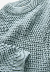 Maglione azzurro chiaro con un maglione spesso e testurizzato, e colletto e polsini a coste. Il tessuto ha un aspetto morbido con un design accogliente.
