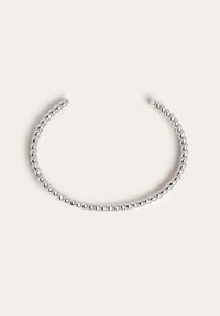 Brazalete de puño de metal plateado con un diseño texturizado de cuentas y un acabado suave y pulido. Cuentas redondas y uniformes rodean la banda.