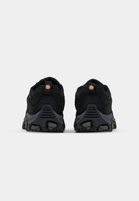 Black athletic shoes with a mesh and suede material, featuring a rugged sole, orange accent on the heel, and a padded collar for comfort.