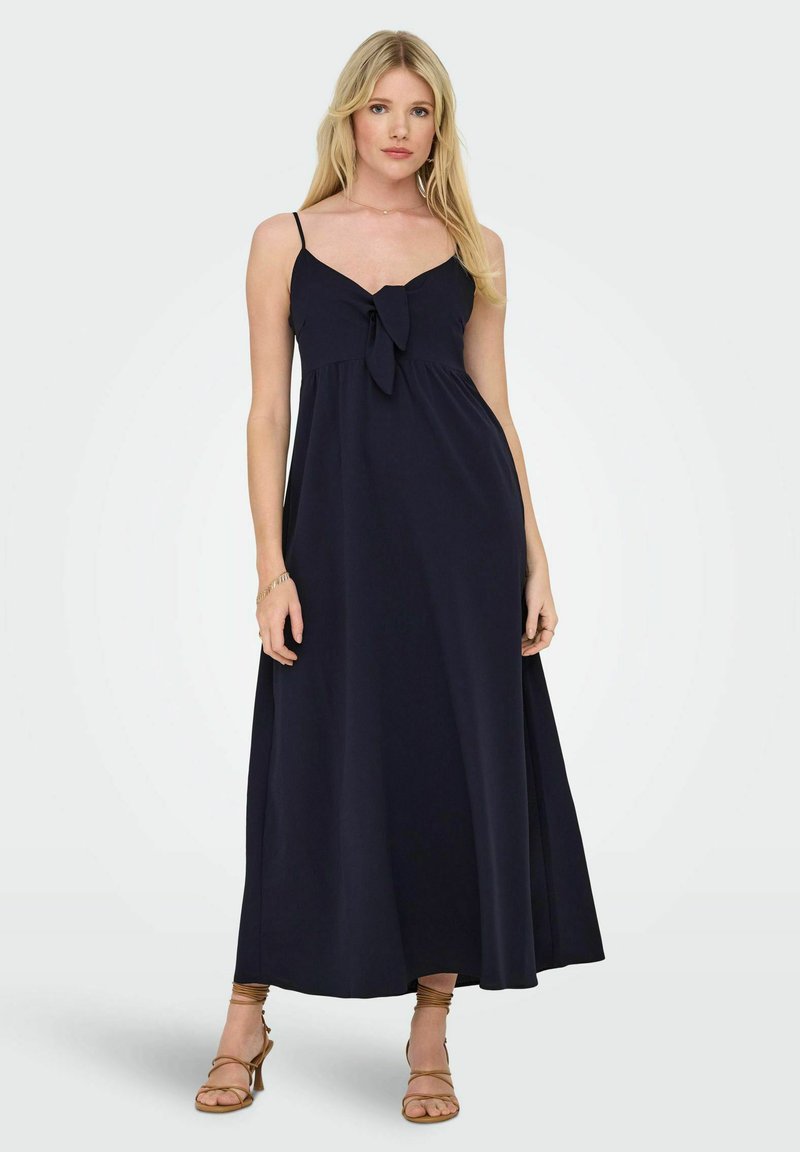 Robe maxi marine à fines bretelles, corsage froncé et nœud à l'avant. Tissu lisse, silhouette fluide et ourlet longueur cheville.