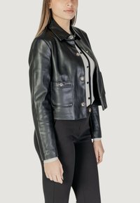 Giacca cropped in pelle nera con colletto, bottoni argentati e due tasche. Morbida al tatto con un design aderente.
