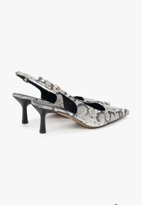Sandały na obcasie typu slingback w czarno-białym wzorze wężowej skóry, z szpiczastym noskiem, teksturowaną skórą, smukłym czarnym obcasem i złotym detale z klamrą.