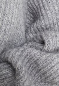 Pehmeä harmaa villakangas, jossa on ribbineulostekstuuri ja vaihtelevia harmaan sävyjä sekä hieman pörröinen pinta. Neulospinta on mukava ja lämmin.