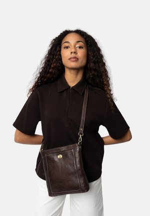 Hnědá kožená crossbody taška s hladkým povrchem, vybavená přední kapsou, mosaznou kovovou výbavou a nastavitelným popruhem.