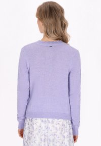 Light purple knitted sweater with long sleeves, featuring a scalloped neckline and a small tag at the back. Soft, textured material.