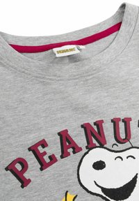 T-shirt in cotone grigia con scollo rotondo e colletto bordeaux, caratterizzata da una grafica di Snoopy e dal testo "PEANUTS" in bold lettere nere.
