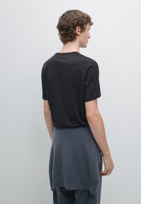 Sort kortærmet t-shirt med rund hals, kombineret med en mørkegrå oversized trøje, der fremviser et lagdelt design og en blød tekstur.