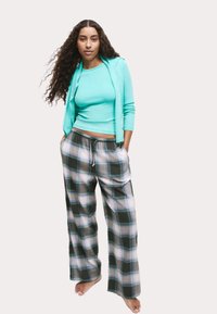 Turquoise getailleerde top en geruite wijde broek met groene, witte en zwarte kleuren. De broek heeft een elastische tailleband en zakken.