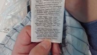 Žymėjimas ant audinio su priežiūros instrukcijomis ir medžiagos sudėtimi: 45% medvilnė, 45% poliesteris. Tekstas atspausdintas keliomis kalbomis.