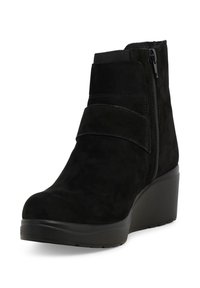 Stivaletto alla caviglia in camoscio nero con punta arrotondata, cerniera laterale e ampia fascia sulla tomaia. Presenta un tacco a zeppa spesso e una superficie testurizzata.