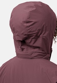 Bordeauxkleurige capuchonjack met een soepel, waterafstotend materiaal. Voorzien van een trekkoord bij de hals en een gestroomlijnd ontwerp zonder zichtbare sluitingen.