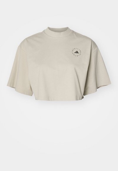 Zkrácené tričko s krátkým rukávem z lehkého béžového bavlněného materiálu. Obsahuje vysoký límec a černé kulaté logo na levé části hrudi.