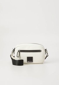 White crossbody bag with a smooth texture, zippered top, and a black adjustable strap. Features a black logo accent on the front.