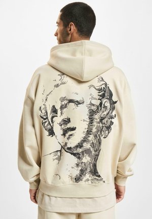 Beige hoodie featuring a large black and gray graphic of a classical sculpture on the back, with a relaxed fit and hood.