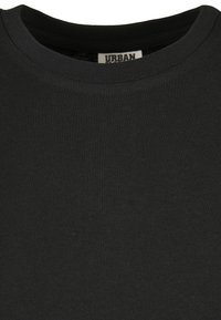 Svart T-shirt med kort ärm och ribbat rundt hals, tillverkad av mjukt tyg. Har en liten etikett med "URBAN" nära kragen.