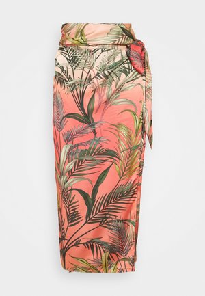 Jupe portefeuille corail avec imprimé de feuilles tropicales vertes et détail noué sur le côté, sur fond blanc.