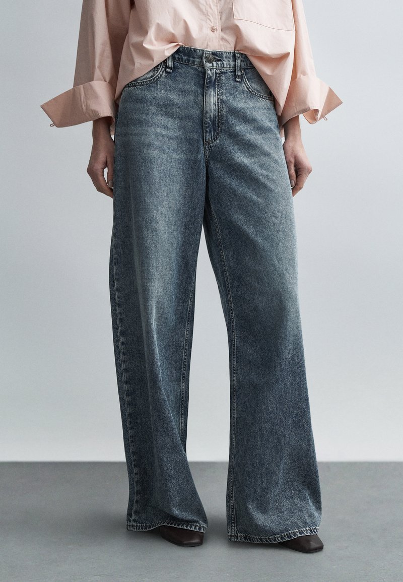 Jeans mit weitem Bein aus ausgewaschenem blauem Denim. Verfügt über eine hohe Taille mit klassischem Knopfverschluss und gerade, lockere Beine. Glatter, leicht texturierter Stoff.