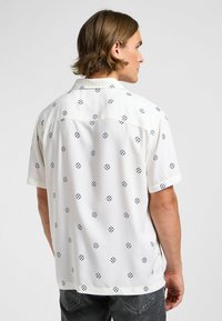 Kortärmad skjorta i lätt tyg, vit med marinblå diamantmönster, har krage och en regular fit-design.