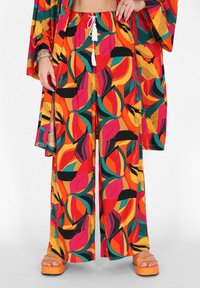 Fel kleuren tweedelig outfit bestaande uit losse broek en een bijpassend top, gemaakt van lichte stof. Kleuren zijn rood, oranje, groen en zwart.