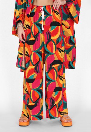 Costum format din două piese, cu un model strălucitor, care include pantaloni largi și un top asortat, realizat dintr-un material ușor. Culorile includ roșu, portocaliu, verde și negru.