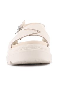 Beige sandaler med kryssende stropper og en teksturert såle. Har en kontrasterende aksent og justerbar spenne for en sikker passform.