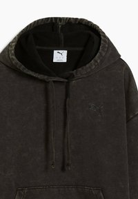 Schwarze Kapuzenjacke mit einer strukturierten, verblichenen Optik; verfügt über einen Kordelzug, eine Vordertasche und ein gesticktes Logodetail. Gefütterte Innenseite der Kapuze.