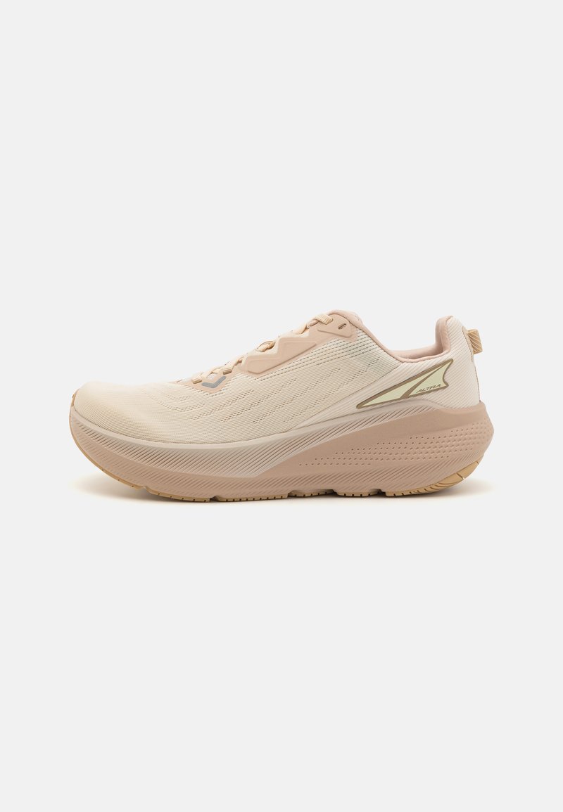 Light beige athletic shoe with a textured mesh upper, rounded sole, and subtle gold accents. Features a lace-up design and cushioned midsole.