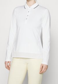 Biała koszula polo z długim rękawem, kołnierzykiem, z listwą na trzy guziki oraz czarnymi akcentami, z panelami siateczkowymi po bokach dla wentylacji.