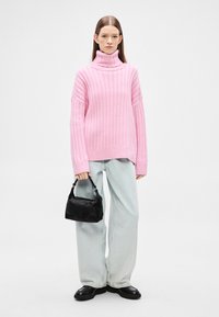 Růžový žebrovaný rolák, široké světle modré džíny, černá texturovaná kabelka a černé platformové boty.