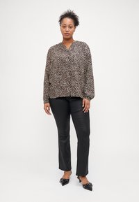 Μπλούζα με leopard print, V λαιμόκοψη και μακριά μανίκια, συνδυασμένη με μαύρο εφαρμοστό παντελόνι και μαύρα γόνατα με μυτερή μύτη. Λείος υφασμάτινος ιστός.