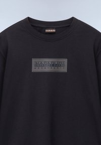 Zwarte katoenen t-shirt met een glanzend rechthoekig logo-embleem met de tekst "NAPAPIJRI geographic" in het wit op de voorkant. Ronde halsontwerp.